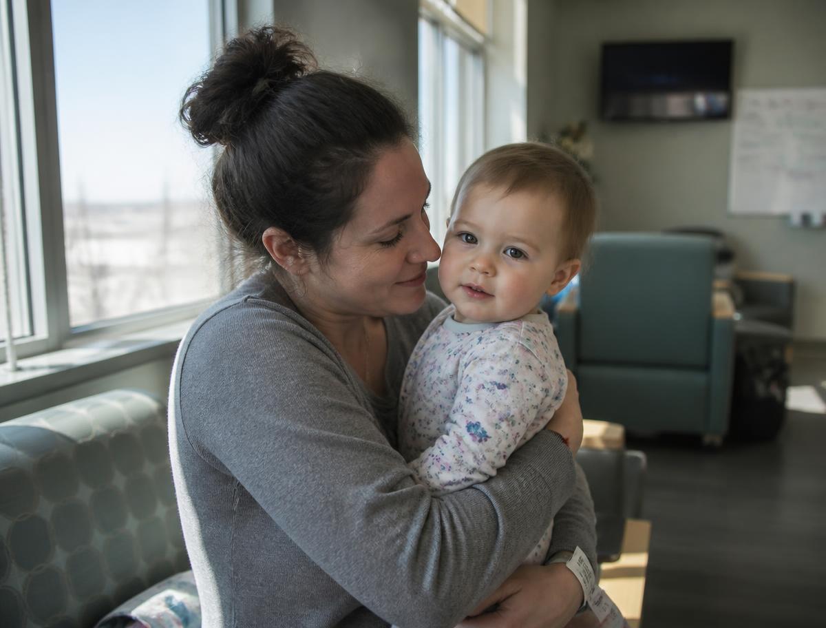 A mother holding her infant in a hospital lounge